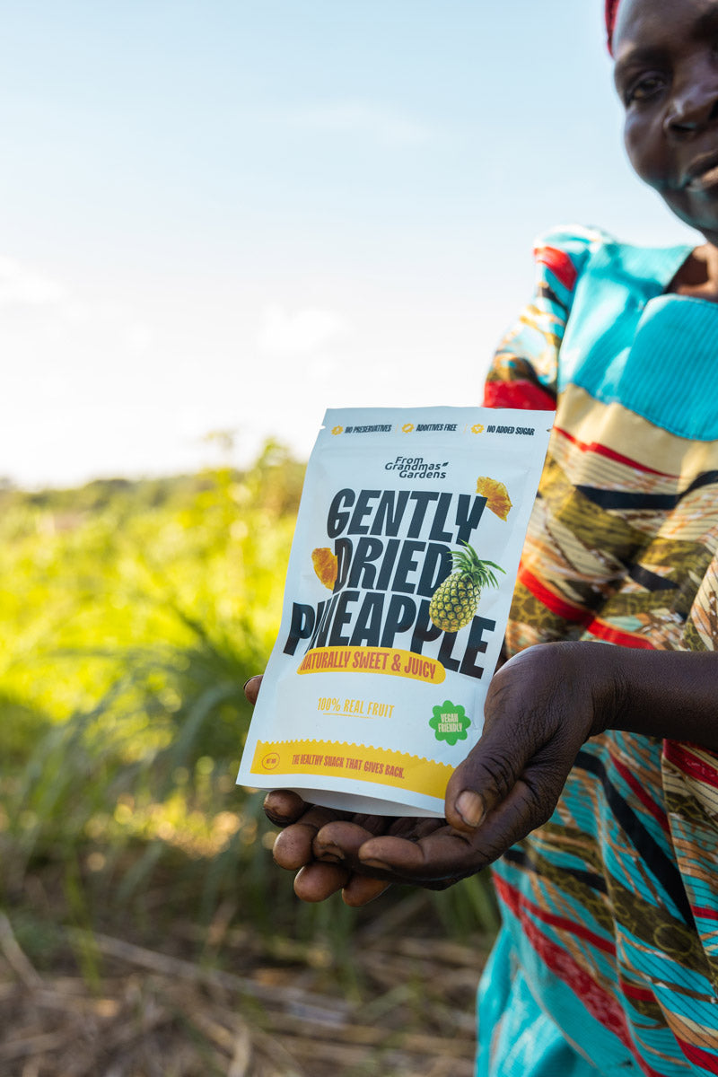 A person holding a package of gently dried pineapple pieces.